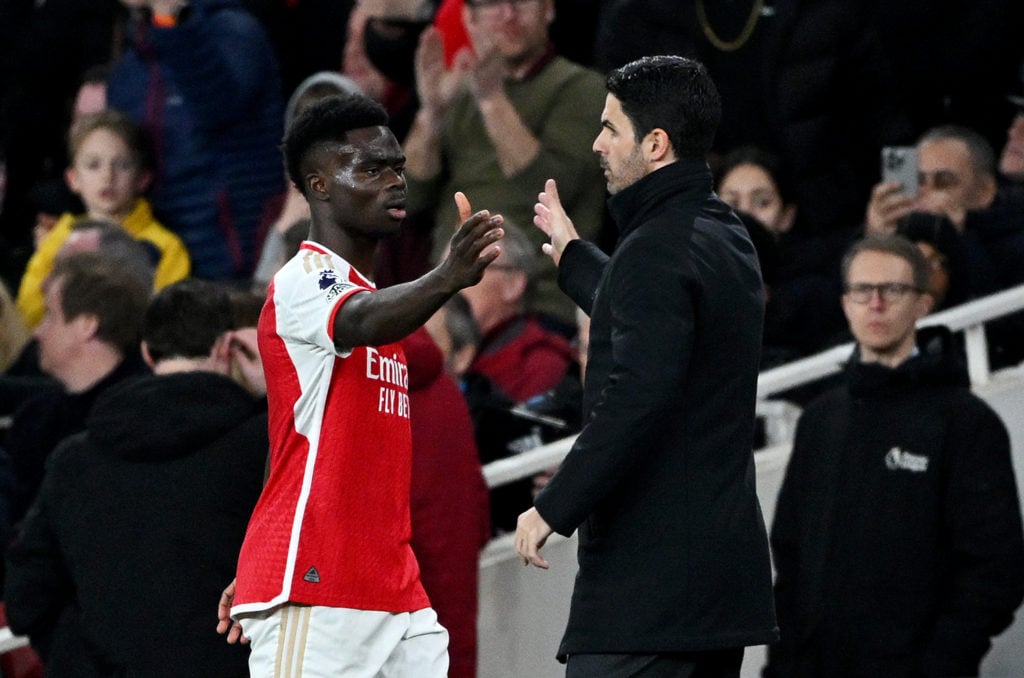 Bukayo Saka of Arsenal interacts with Mikel Arteta, Manager of Arsenal, as he leaves the field after sustaining an injury during the Premier League...